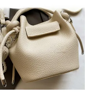 Close-up of creamy white litchi grain leather bucket bag with pearl and knot details