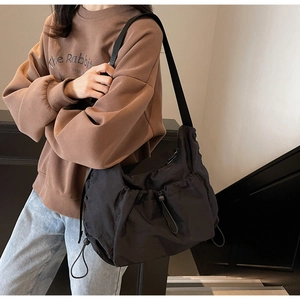 Detailed close-up of a black nylon crossbody bag featuring a unique drawstring pleated design