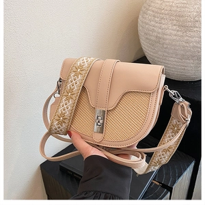 Detail of saddle bag showing woven texture, smooth leather contrast, and metal clasp