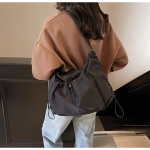 Detail of black large capacity tote bag with adjustable strap and drawstring design