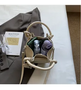 Top view of beige bucket bag interior showing phone, skincare, and folded umbrella