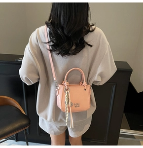 Détail du mini sac seau rose avec lettres argentées, foulard en soie et bandoulière