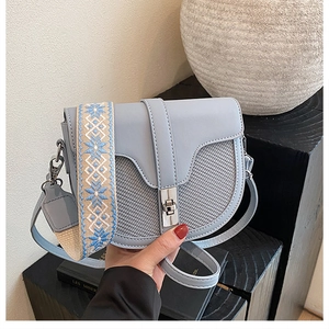 Close-up of contrast saddle bag with embroidered strap and silver twist lock detail