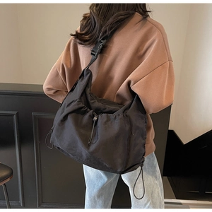 Detail of black drawstring crossbody bag with buckle strap and techwear design style