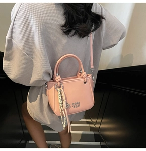 Vue détaillée d'un sac seau rose clair avec corde tressée et logo métallique