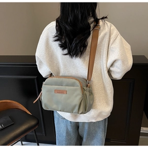 Detail of grey-green nylon crossbody bag with brown leather trim and HPSC logo