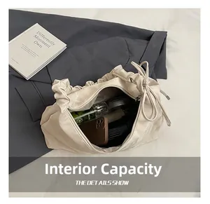 Vista dettagliata dell'interno capiente della borsa tote beige a pieghe con oggetti personali