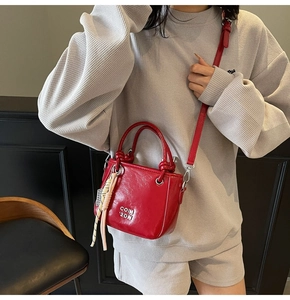 Détail d'un mini sac à main rouge brillant avec anses rondes et ruban décoratif