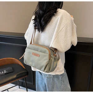 Olive green nylon crossbody bag showing adjustable shoulder strap and large capacity