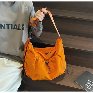 Close-up of bright orange nylon pleated bag with adjustable strap and plastic buckle