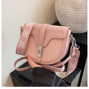 Detail of pink saddle bag featuring woven texture and ethnic style embroidered strap