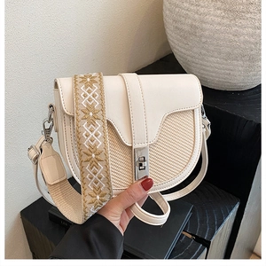 Detail of minimalist saddle bag featuring cream leather and textured woven contrast