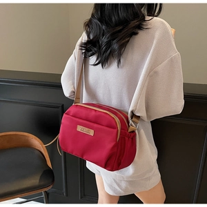 Crossbody bag detail showing red nylon fabric layers and adjustable woven strap