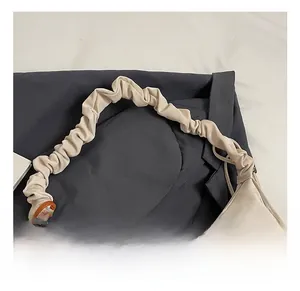 Dettaglio del manico arricciato e della trama in nylon di una borsa tote beige