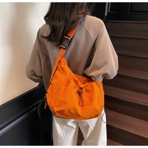Close-up of bright orange crossbody bag featuring adjustable drawstring and wide shoulder strap