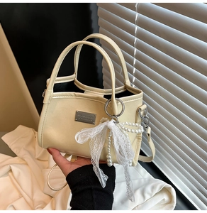 Detail of cream PU leather handbag with lace bow and pearl pendant accessories