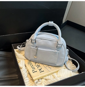 Dettaglio borsa bowling celeste con texture a grana e pendente a cuore in scatola