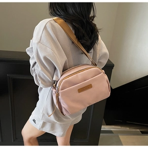Detail of mauve crossbody nylon bag shown on model with adjustable wide shoulder strap