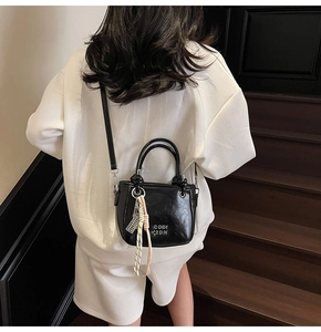 Sac seau noir chic avec gaufrage COIN 2DN et détail gland porté par mannequin sur escalier