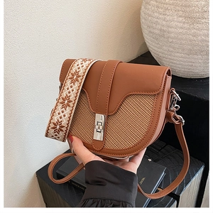 Detail of retro saddle bag with straw texture contrast and ethnic style wide strap