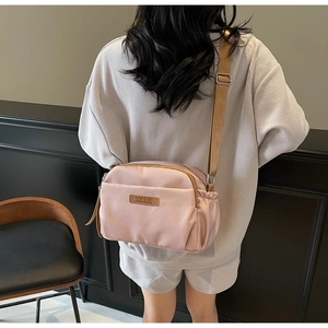 Detail of pink nylon crossbody bag featuring an adjustable strap and side pocket