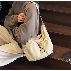 Detail of cream drawstring nylon dumpling bag with adjustable elastic cords