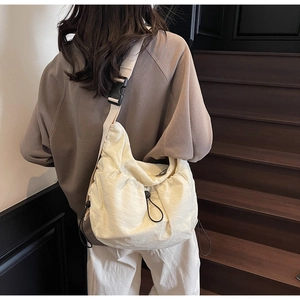 Detail of adjustable wide shoulder strap and buckle on cream crescent pleated bag