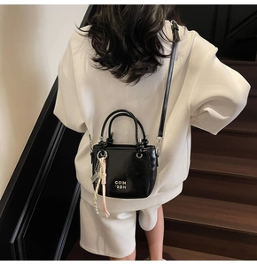 Détail du mini sac seau en cuir verni noir brillant avec finition métallique élégante