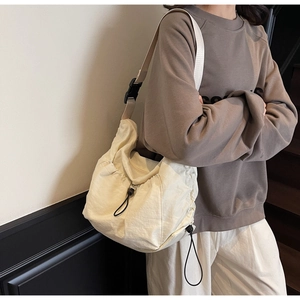 Detail of cream-colored pleated crossbody bag with adjustable wide strap and buckle