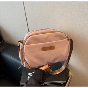 Detail of dusty rose crossbody bag with three zipper compartments and adjustable strap