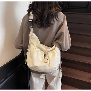 Close-up of the beige nylon crossbody bag featuring functional drawstring and wide strap