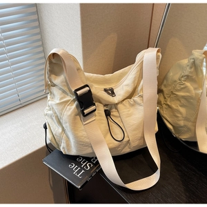 Detail of creamy white pleated nylon crossbody bag with buckle and drawstring pocket