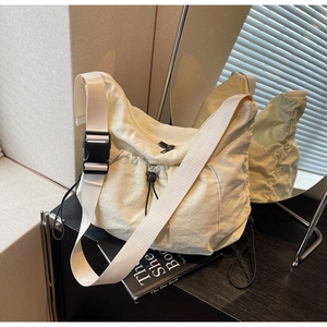 Detail of off-white nylon crossbody bag with tactical buckle and functional drawstring