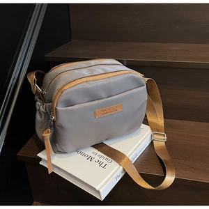 Macro shot of grey multi-zipper crossbody bag with adjustable brown shoulder strap