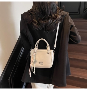 Détail d'un sac seau chic en PU beige avec foulard en soie et lettres métalliques