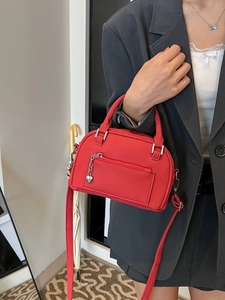 Borsa Boston rossa in pelle con ciondolo a cuore indossata da modella in blazer grigio