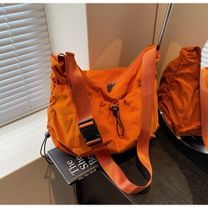 Detail view of bright orange waterproof nylon crossbody bag with adjustable wide strap
