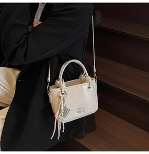 Vue détaillée du sac seau blanc cassé avec pendentif tressé et texture en cuir