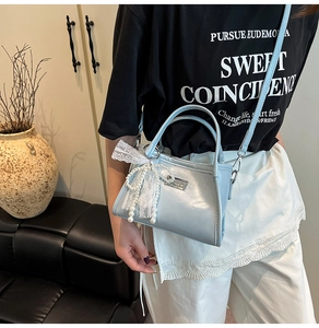 Detail of light blue faux leather bag with pearl lace bow charm and silver nameplate