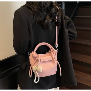 Close-up of pink lychee grain bucket bag with pearl and bow charm on model