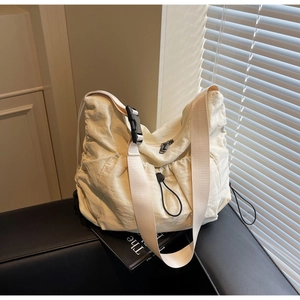 Detail view of cream pleated crossbody bag with wide adjustable strap and metal zipper