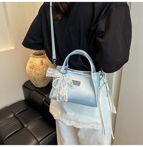 Detail view of the light blue pearl-finish handbag with lace bow and metal logo tag