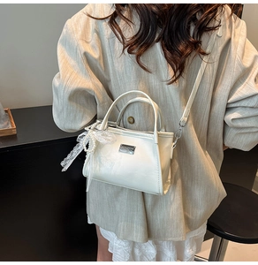 Detail of a creamy white PU leather crossbody bag with lace and pearl charm decorations