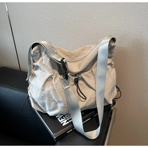 Detail of grey pleated nylon crossbody bag with black buckle strap and drawstring closure
