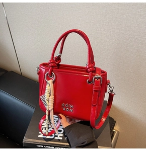 Détail d'un sac seau en cuir verni rouge brillant avec logo argenté et pendentif