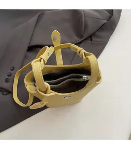 Dettaglio della borsa a secchiello in pelle gialla con trama a grana e chiusura magnetica