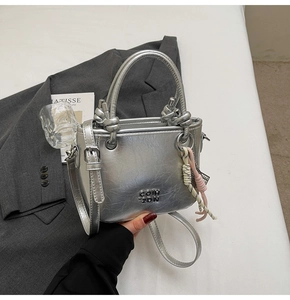 Détail du sac seau argenté métallisé avec breloque en corde et logo de marque