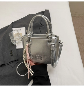 Gros plan d'un mini sac cabas argenté avec poignée nouée et pompon tissé décoratif élégant