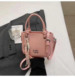 Vue détaillée du sac seau en cuir rose avec poignée nouée et ornements en métal argenté