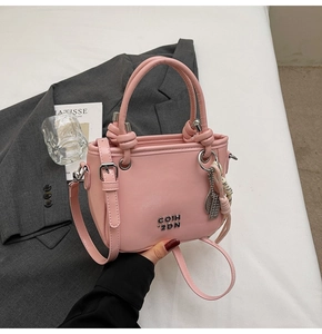 Détail du sac à main en cuir PU rose clair avec poignée nouée et logo en métal argenté